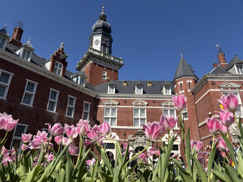 ハウステンボス内。チューリップ越しにヨーロッパ風の赤レンガ建築を見上げた構図